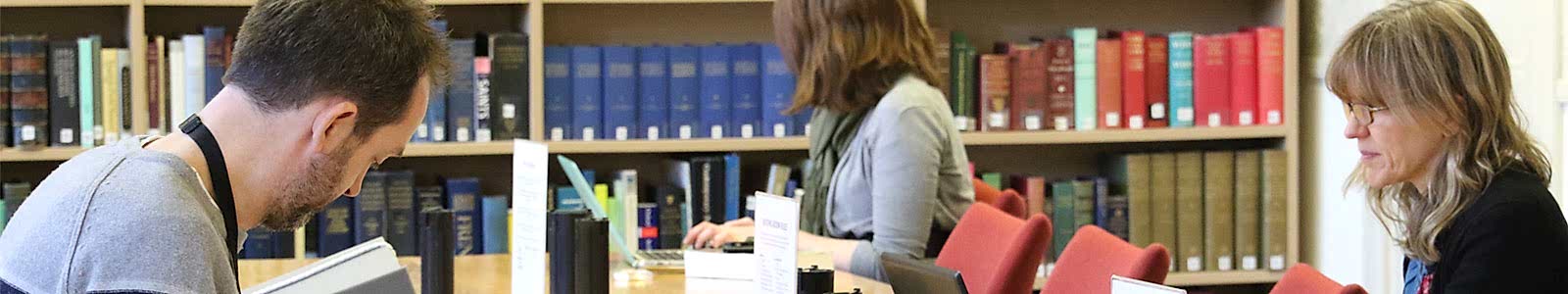 Three people sitting at a table in front of a bookcase.