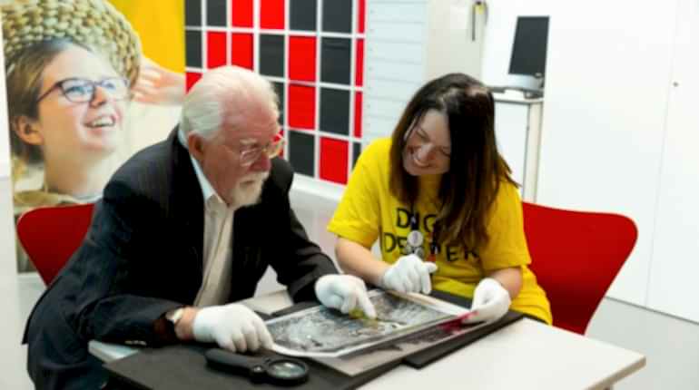 Two people looking at a collection object at The MERL