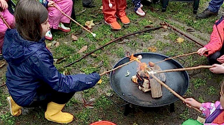 Families toasting marshmallows in the MERL garden during a Green Explorers session