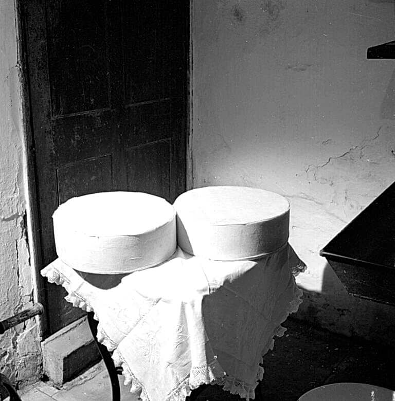 Two round cheeses, Double Gloucester, on a table with a white tablecloth